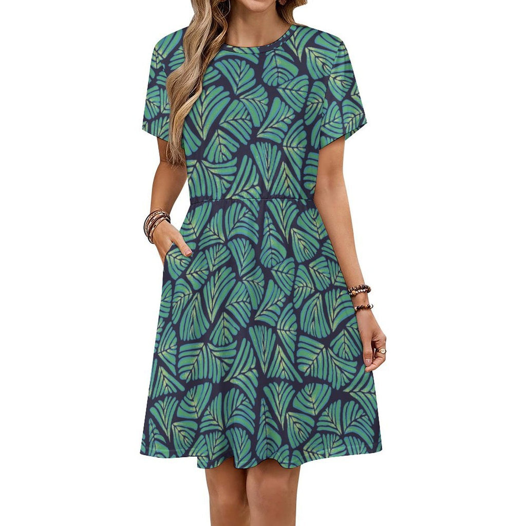 Short sleeve dress featuring the Frondescence pattern with layered tropical foliage in deep green botanical tones and an all-over nature-inspired print. Flowy casual dress with earthy jungle aesthetic, maximalist fashion, indie streetwear, botanical artwork, expressive queer friendly style, artsy everyday wear, and retro-inspired tropical clothing perfect for vacations, brunch, festivals, casual outings, and comfortable everyday alternative fashion.