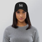 Black dad hat embroidered with the word ‘HAG’ in ornate vintage gothic lettering. Alternative fashion accessory with queer streetwear aesthetic, witchy fashion, sarcastic humor, feminist style, indie fashion, spooky cute apparel, gothic embroidery, punk inspired streetwear, adjustable baseball cap, casual everyday alternative outfit, internet humor fashion, artsy accessory, and edgy statement hat for concerts, festivals, casual wear, and alternative wardrobes.