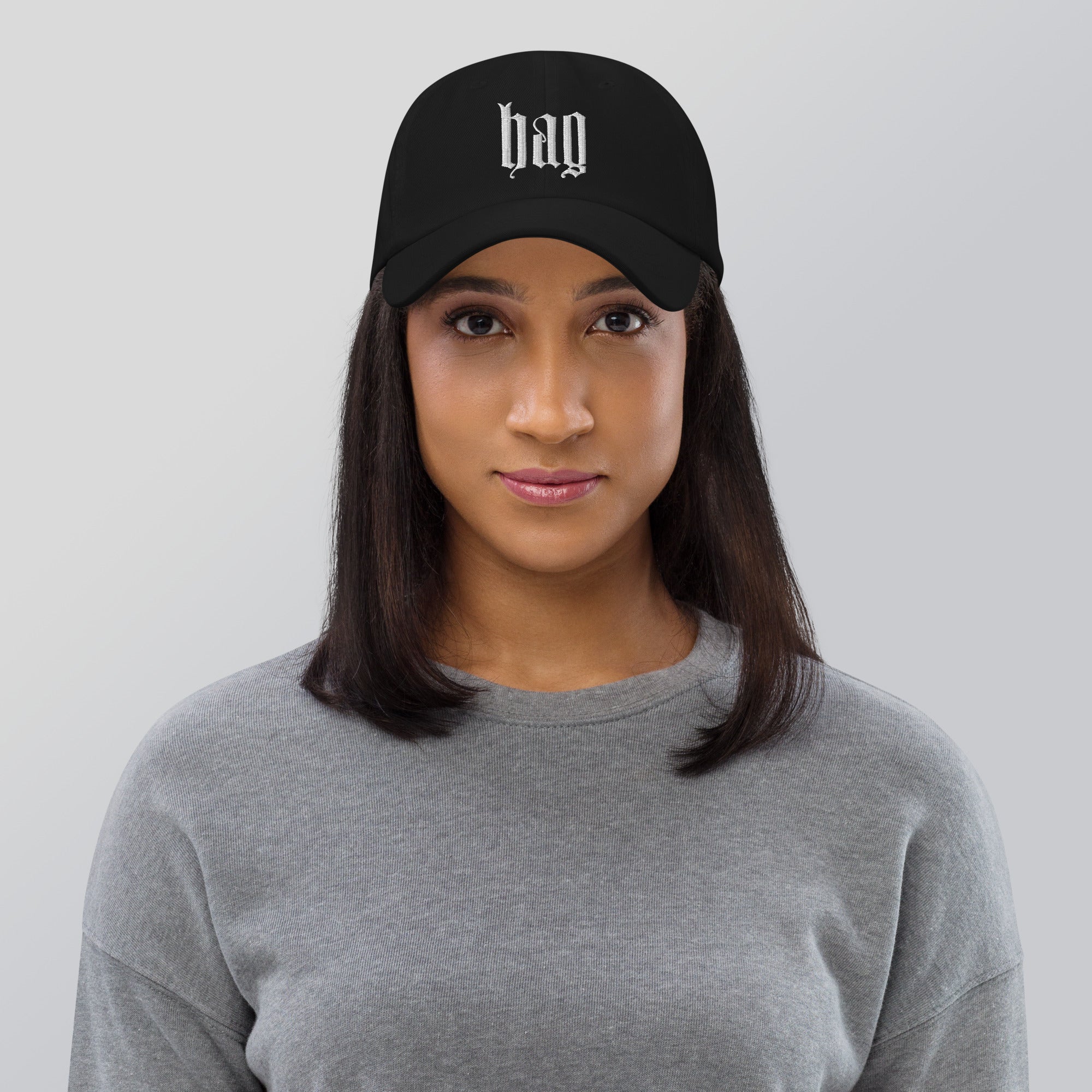 Black dad hat embroidered with the word ‘HAG’ in ornate vintage gothic lettering. Alternative fashion accessory with queer streetwear aesthetic, witchy fashion, sarcastic humor, feminist style, indie fashion, spooky cute apparel, gothic embroidery, punk inspired streetwear, adjustable baseball cap, casual everyday alternative outfit, internet humor fashion, artsy accessory, and edgy statement hat for concerts, festivals, casual wear, and alternative wardrobes.