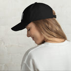 Black dad hat embroidered with the word ‘HAG’ in ornate vintage gothic lettering. Alternative fashion accessory with queer streetwear aesthetic, witchy fashion, sarcastic humor, feminist style, indie fashion, spooky cute apparel, gothic embroidery, punk inspired streetwear, adjustable baseball cap, casual everyday alternative outfit, internet humor fashion, artsy accessory, and edgy statement hat for concerts, festivals, casual wear, and alternative wardrobes.