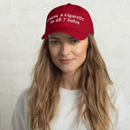 Baseball cap embroidered with the phrase ‘I Have a Cigarette in All 7 Holes’ in ornate vintage gothic lettering. Alternative fashion accessory with edgy internet humor, queer streetwear aesthetic, punk inspired style, ironic meme fashion, tattoo inspired typography, goth streetwear, adjustable dad hat, casual alternative outfit accessory, artsy statement cap, chaotic humor apparel, indie fashion, and expressive alternative clothing for concerts, festivals, everyday wear, and alternative wardrobes.