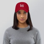 Black dad hat embroidered with the word ‘HAG’ in ornate vintage gothic lettering. Alternative fashion accessory with queer streetwear aesthetic, witchy fashion, sarcastic humor, feminist style, indie fashion, spooky cute apparel, gothic embroidery, punk inspired streetwear, adjustable baseball cap, casual everyday alternative outfit, internet humor fashion, artsy accessory, and edgy statement hat for concerts, festivals, casual wear, and alternative wardrobes.