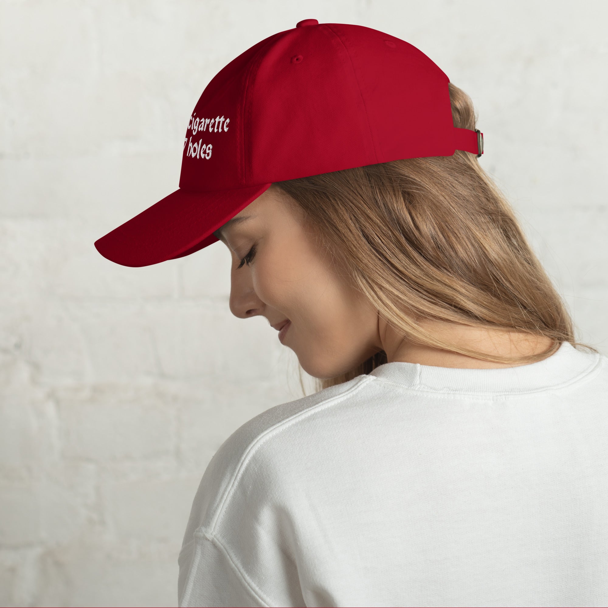 Baseball cap embroidered with the phrase ‘I Have a Cigarette in All 7 Holes’ in ornate vintage gothic lettering. Alternative fashion accessory with edgy internet humor, queer streetwear aesthetic, punk inspired style, ironic meme fashion, tattoo inspired typography, goth streetwear, adjustable dad hat, casual alternative outfit accessory, artsy statement cap, chaotic humor apparel, indie fashion, and expressive alternative clothing for concerts, festivals, everyday wear, and alternative wardrobes.