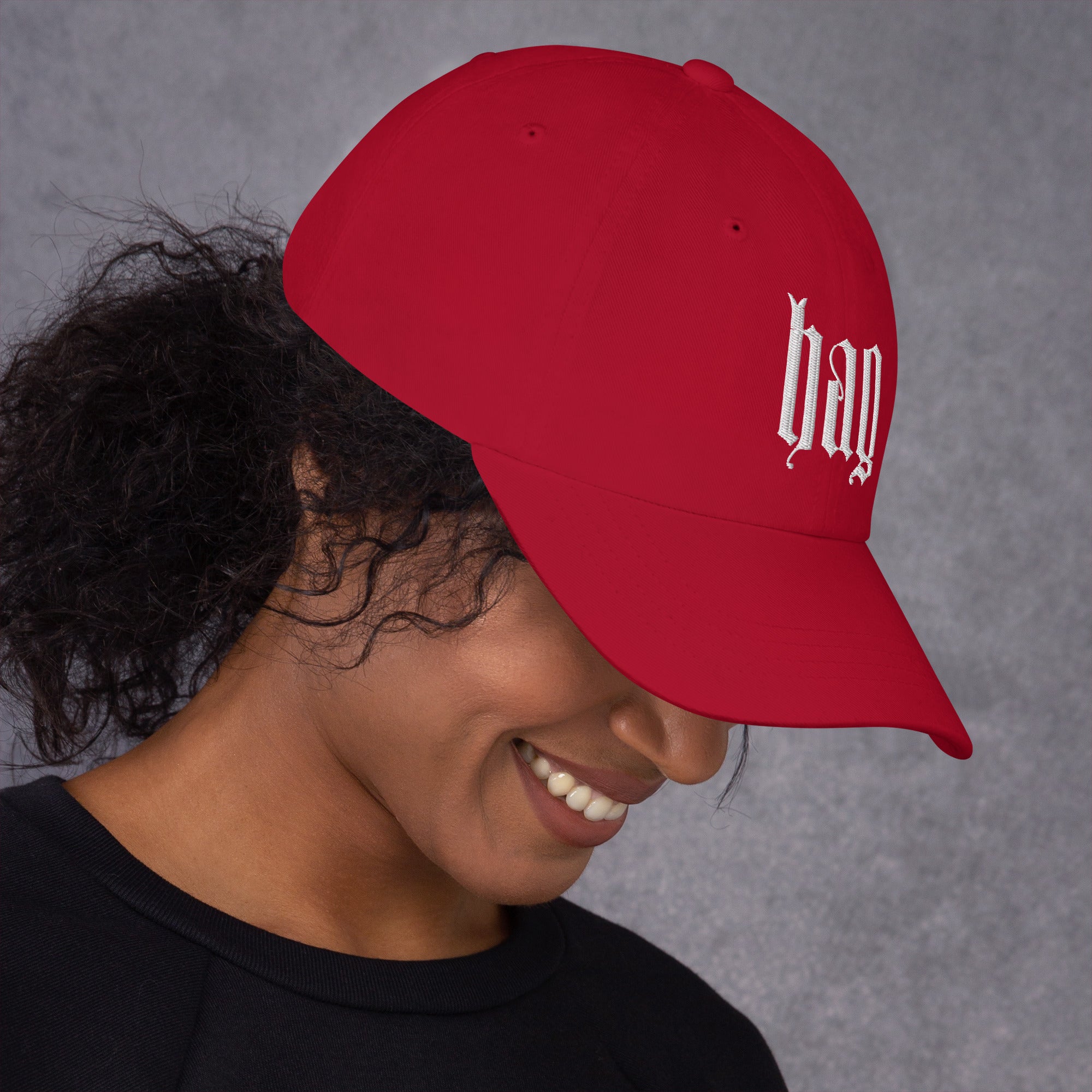 Black dad hat embroidered with the word ‘HAG’ in ornate vintage gothic lettering. Alternative fashion accessory with queer streetwear aesthetic, witchy fashion, sarcastic humor, feminist style, indie fashion, spooky cute apparel, gothic embroidery, punk inspired streetwear, adjustable baseball cap, casual everyday alternative outfit, internet humor fashion, artsy accessory, and edgy statement hat for concerts, festivals, casual wear, and alternative wardrobes.