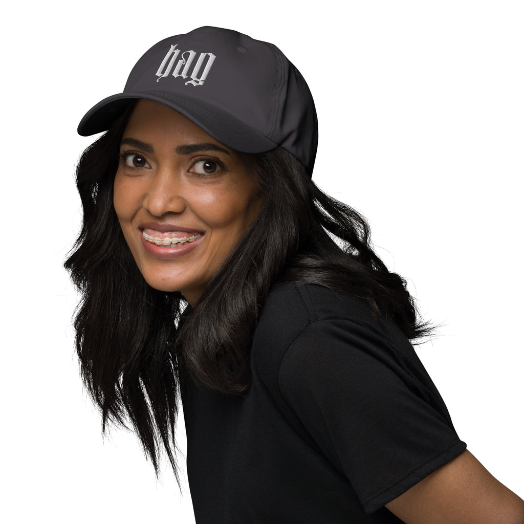 Black dad hat embroidered with the word ‘HAG’ in ornate vintage gothic lettering. Alternative fashion accessory with queer streetwear aesthetic, witchy fashion, sarcastic humor, feminist style, indie fashion, spooky cute apparel, gothic embroidery, punk inspired streetwear, adjustable baseball cap, casual everyday alternative outfit, internet humor fashion, artsy accessory, and edgy statement hat for concerts, festivals, casual wear, and alternative wardrobes.
