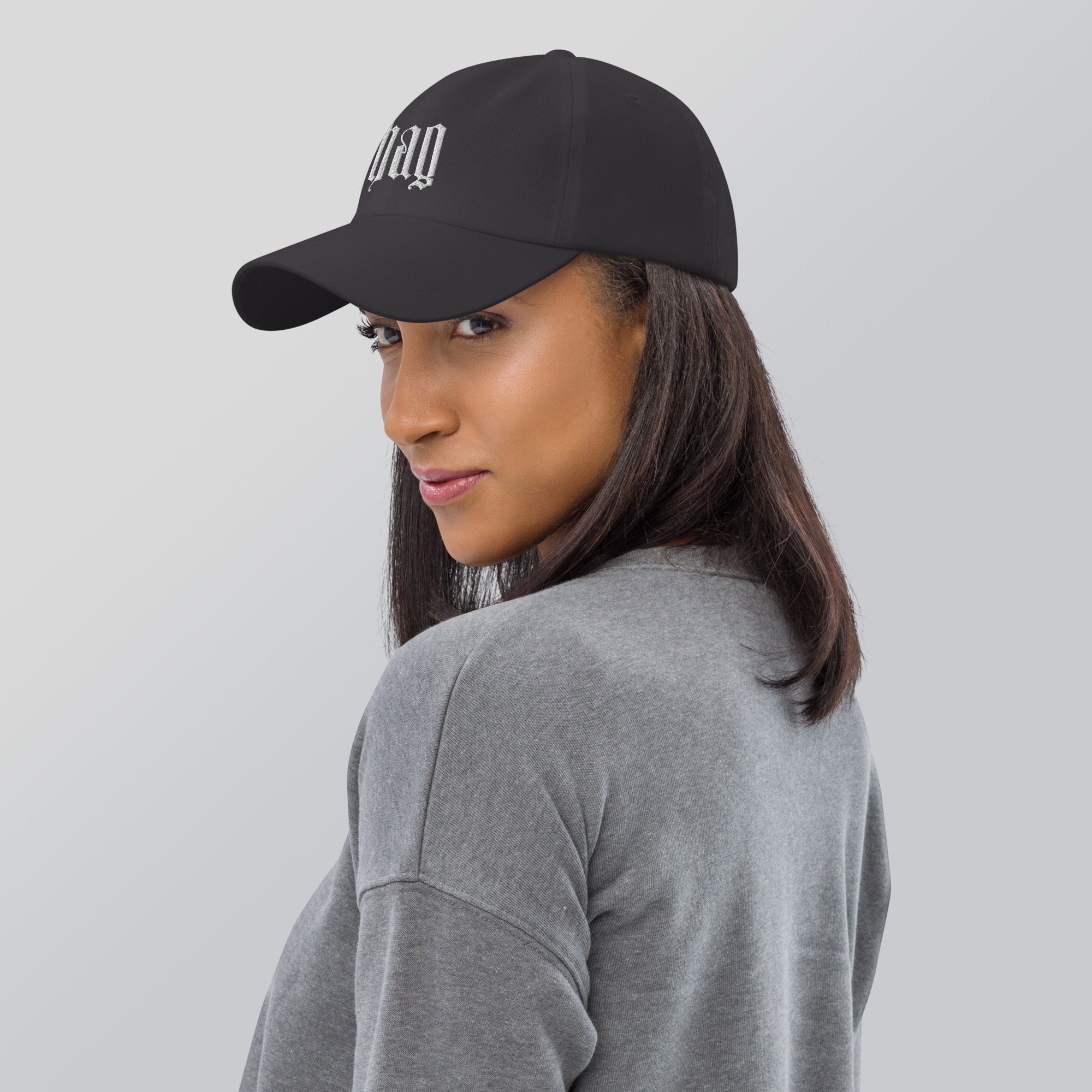 Black dad hat embroidered with the word ‘HAG’ in ornate vintage gothic lettering. Alternative fashion accessory with queer streetwear aesthetic, witchy fashion, sarcastic humor, feminist style, indie fashion, spooky cute apparel, gothic embroidery, punk inspired streetwear, adjustable baseball cap, casual everyday alternative outfit, internet humor fashion, artsy accessory, and edgy statement hat for concerts, festivals, casual wear, and alternative wardrobes.