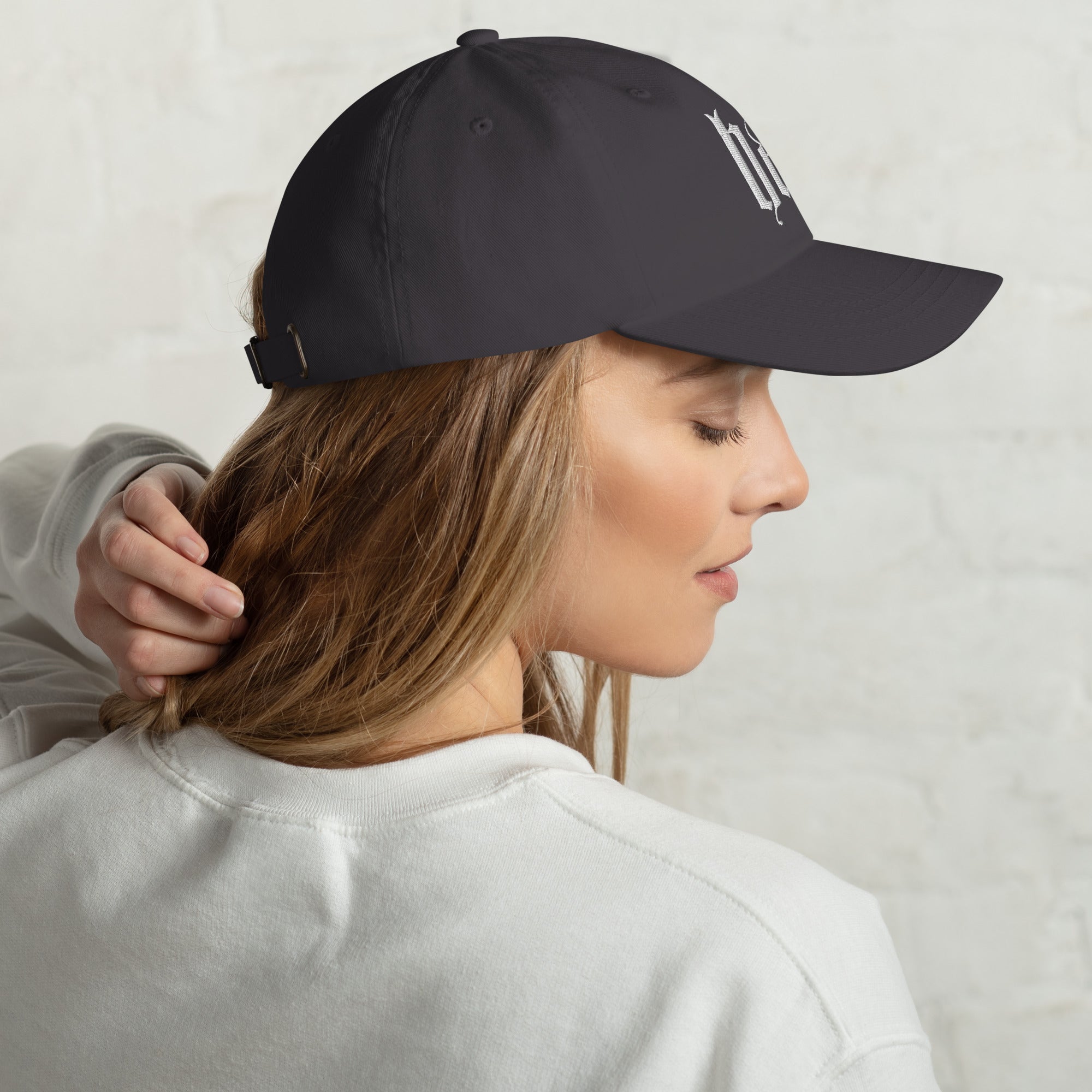 Black dad hat embroidered with the word ‘HAG’ in ornate vintage gothic lettering. Alternative fashion accessory with queer streetwear aesthetic, witchy fashion, sarcastic humor, feminist style, indie fashion, spooky cute apparel, gothic embroidery, punk inspired streetwear, adjustable baseball cap, casual everyday alternative outfit, internet humor fashion, artsy accessory, and edgy statement hat for concerts, festivals, casual wear, and alternative wardrobes.