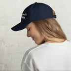 Baseball cap embroidered with the phrase ‘I Have a Cigarette in All 7 Holes’ in ornate vintage gothic lettering. Alternative fashion accessory with edgy internet humor, queer streetwear aesthetic, punk inspired style, ironic meme fashion, tattoo inspired typography, goth streetwear, adjustable dad hat, casual alternative outfit accessory, artsy statement cap, chaotic humor apparel, indie fashion, and expressive alternative clothing for concerts, festivals, everyday wear, and alternative wardrobes.