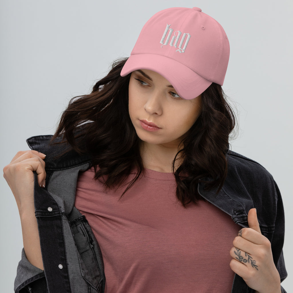 Black dad hat embroidered with the word ‘HAG’ in ornate vintage gothic lettering. Alternative fashion accessory with queer streetwear aesthetic, witchy fashion, sarcastic humor, feminist style, indie fashion, spooky cute apparel, gothic embroidery, punk inspired streetwear, adjustable baseball cap, casual everyday alternative outfit, internet humor fashion, artsy accessory, and edgy statement hat for concerts, festivals, casual wear, and alternative wardrobes.