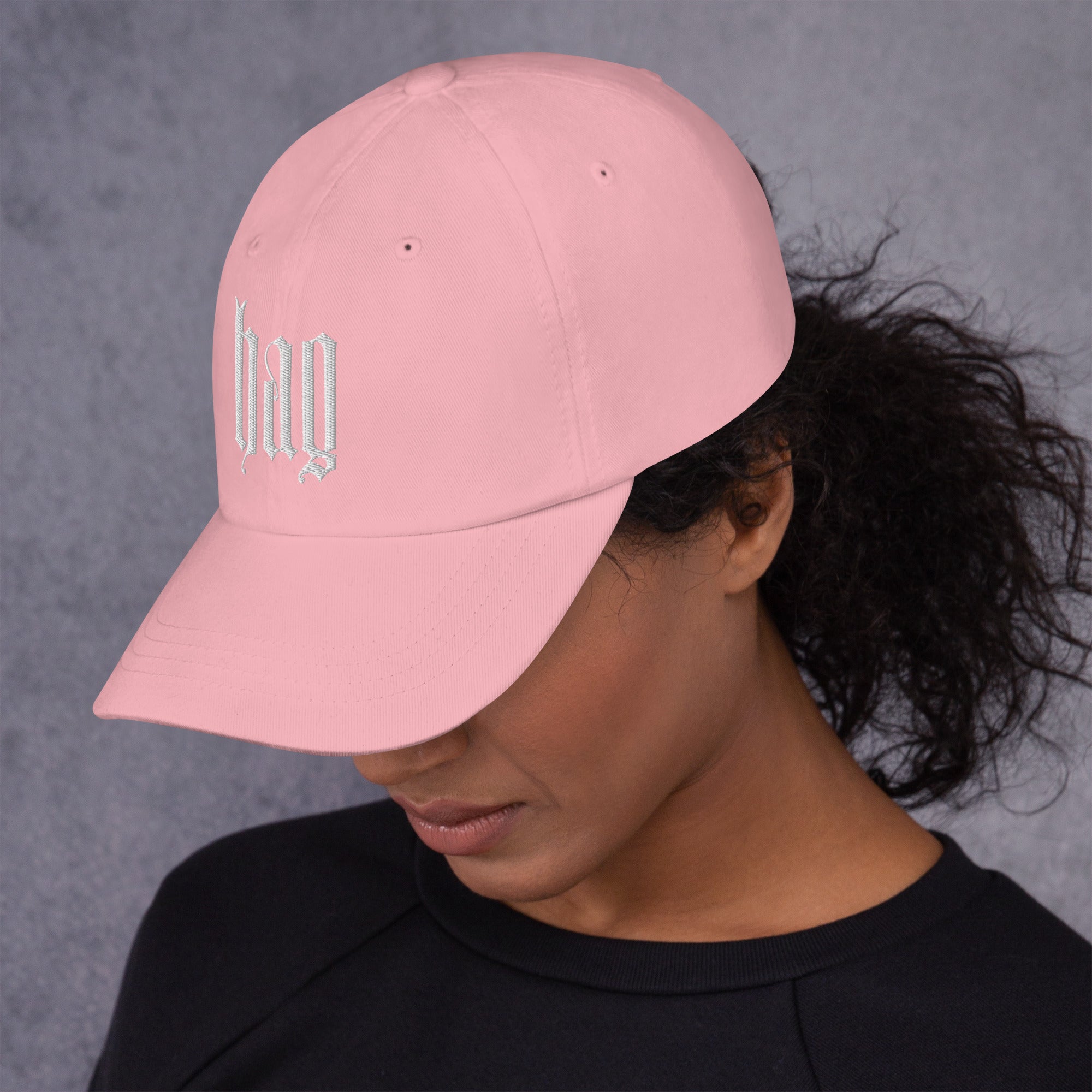 Black dad hat embroidered with the word ‘HAG’ in ornate vintage gothic lettering. Alternative fashion accessory with queer streetwear aesthetic, witchy fashion, sarcastic humor, feminist style, indie fashion, spooky cute apparel, gothic embroidery, punk inspired streetwear, adjustable baseball cap, casual everyday alternative outfit, internet humor fashion, artsy accessory, and edgy statement hat for concerts, festivals, casual wear, and alternative wardrobes.