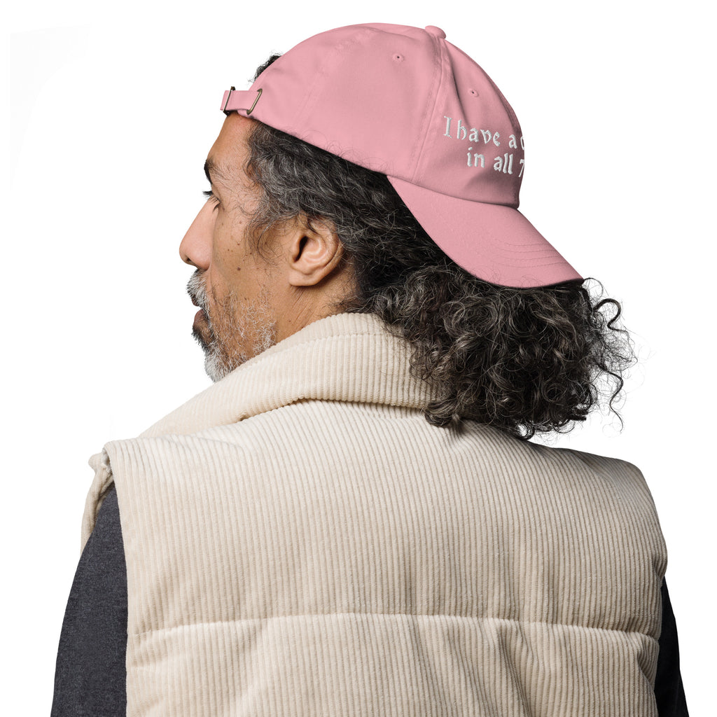 Baseball cap embroidered with the phrase ‘I Have a Cigarette in All 7 Holes’ in ornate vintage gothic lettering. Alternative fashion accessory with edgy internet humor, queer streetwear aesthetic, punk inspired style, ironic meme fashion, tattoo inspired typography, goth streetwear, adjustable dad hat, casual alternative outfit accessory, artsy statement cap, chaotic humor apparel, indie fashion, and expressive alternative clothing for concerts, festivals, everyday wear, and alternative wardrobes.