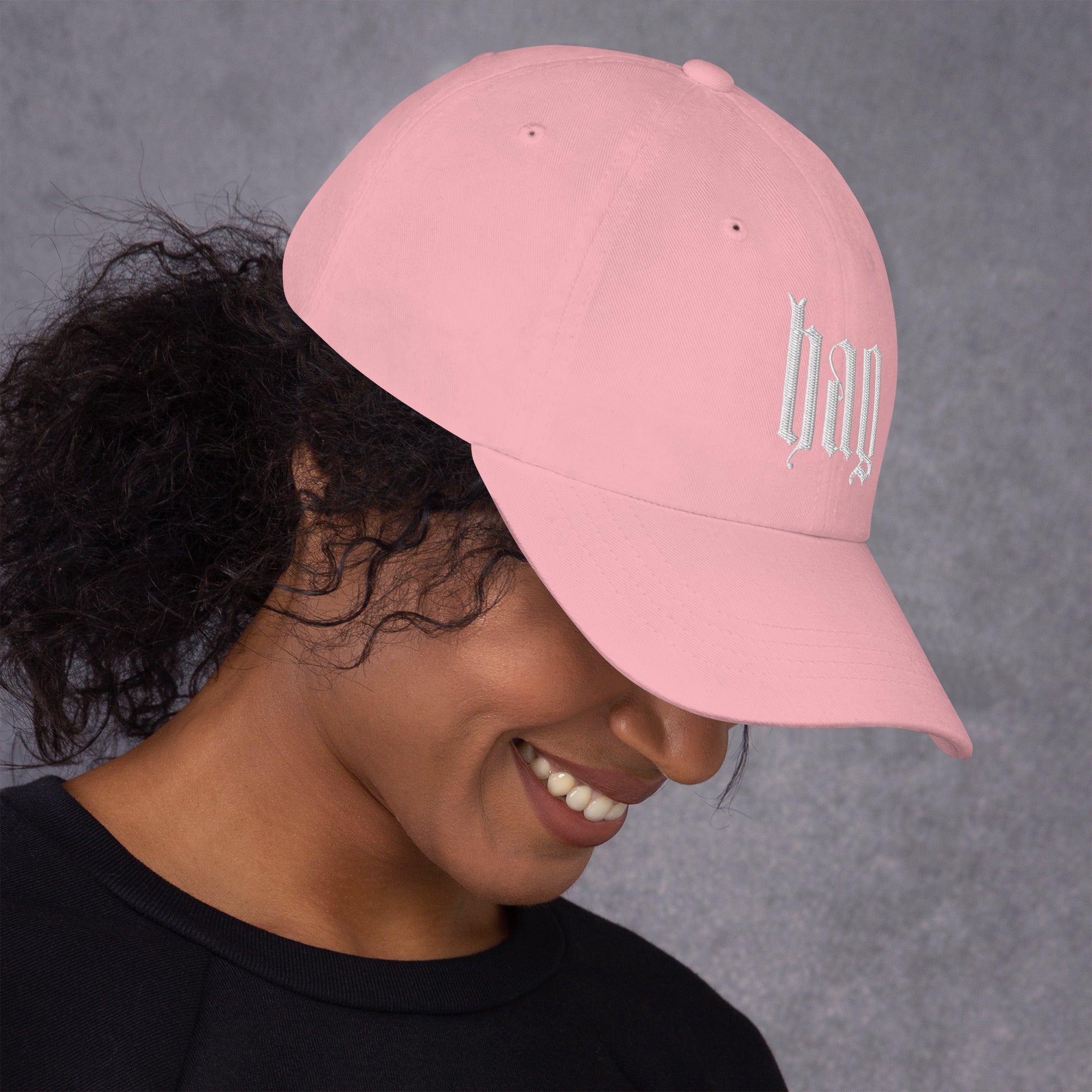 Black dad hat embroidered with the word ‘HAG’ in ornate vintage gothic lettering. Alternative fashion accessory with queer streetwear aesthetic, witchy fashion, sarcastic humor, feminist style, indie fashion, spooky cute apparel, gothic embroidery, punk inspired streetwear, adjustable baseball cap, casual everyday alternative outfit, internet humor fashion, artsy accessory, and edgy statement hat for concerts, festivals, casual wear, and alternative wardrobes.