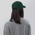 Black dad hat embroidered with the word ‘HAG’ in ornate vintage gothic lettering. Alternative fashion accessory with queer streetwear aesthetic, witchy fashion, sarcastic humor, feminist style, indie fashion, spooky cute apparel, gothic embroidery, punk inspired streetwear, adjustable baseball cap, casual everyday alternative outfit, internet humor fashion, artsy accessory, and edgy statement hat for concerts, festivals, casual wear, and alternative wardrobes.