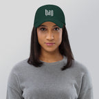 Black dad hat embroidered with the word ‘HAG’ in ornate vintage gothic lettering. Alternative fashion accessory with queer streetwear aesthetic, witchy fashion, sarcastic humor, feminist style, indie fashion, spooky cute apparel, gothic embroidery, punk inspired streetwear, adjustable baseball cap, casual everyday alternative outfit, internet humor fashion, artsy accessory, and edgy statement hat for concerts, festivals, casual wear, and alternative wardrobes.