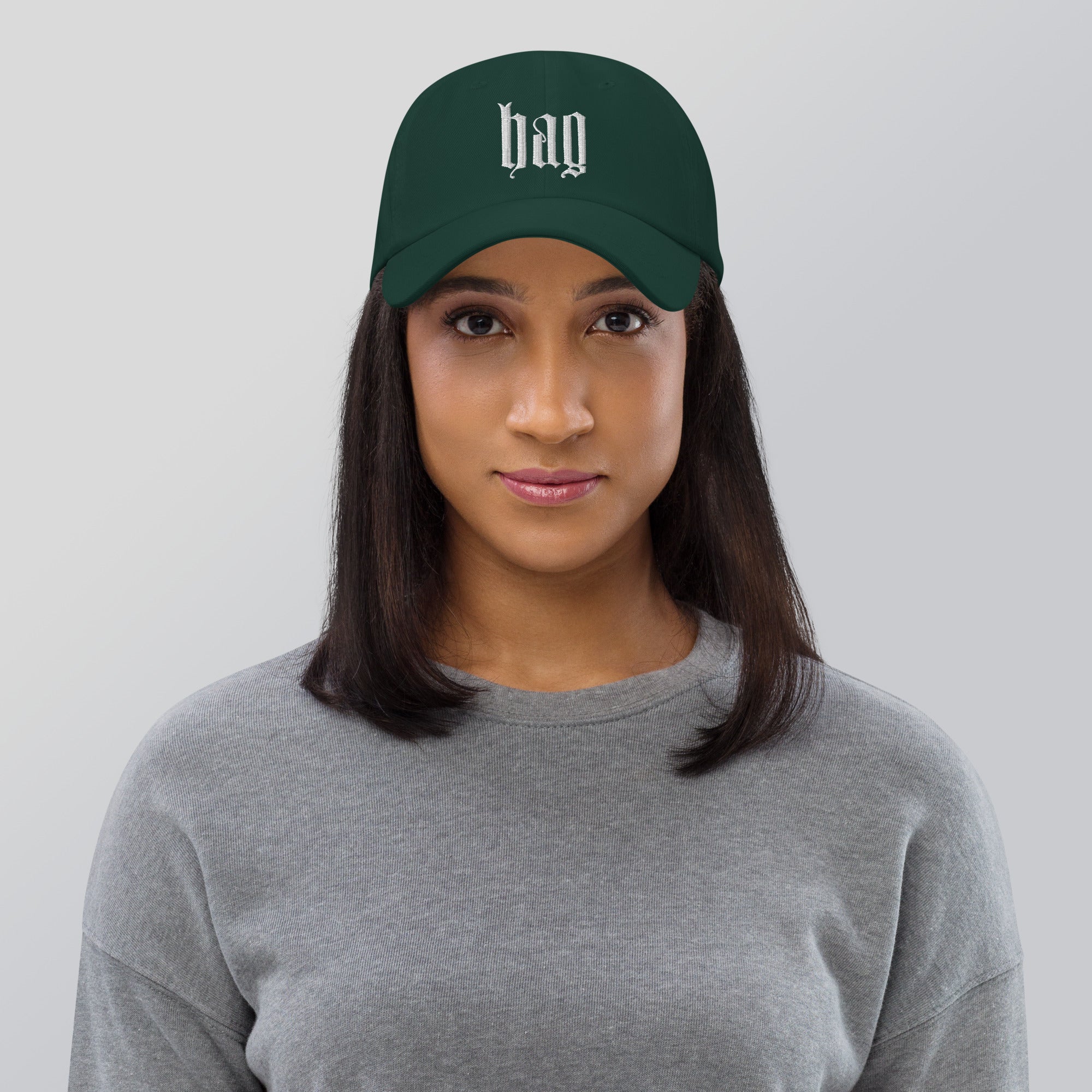 Black dad hat embroidered with the word ‘HAG’ in ornate vintage gothic lettering. Alternative fashion accessory with queer streetwear aesthetic, witchy fashion, sarcastic humor, feminist style, indie fashion, spooky cute apparel, gothic embroidery, punk inspired streetwear, adjustable baseball cap, casual everyday alternative outfit, internet humor fashion, artsy accessory, and edgy statement hat for concerts, festivals, casual wear, and alternative wardrobes.