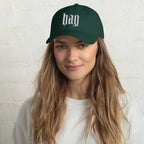 Black dad hat embroidered with the word ‘HAG’ in ornate vintage gothic lettering. Alternative fashion accessory with queer streetwear aesthetic, witchy fashion, sarcastic humor, feminist style, indie fashion, spooky cute apparel, gothic embroidery, punk inspired streetwear, adjustable baseball cap, casual everyday alternative outfit, internet humor fashion, artsy accessory, and edgy statement hat for concerts, festivals, casual wear, and alternative wardrobes.