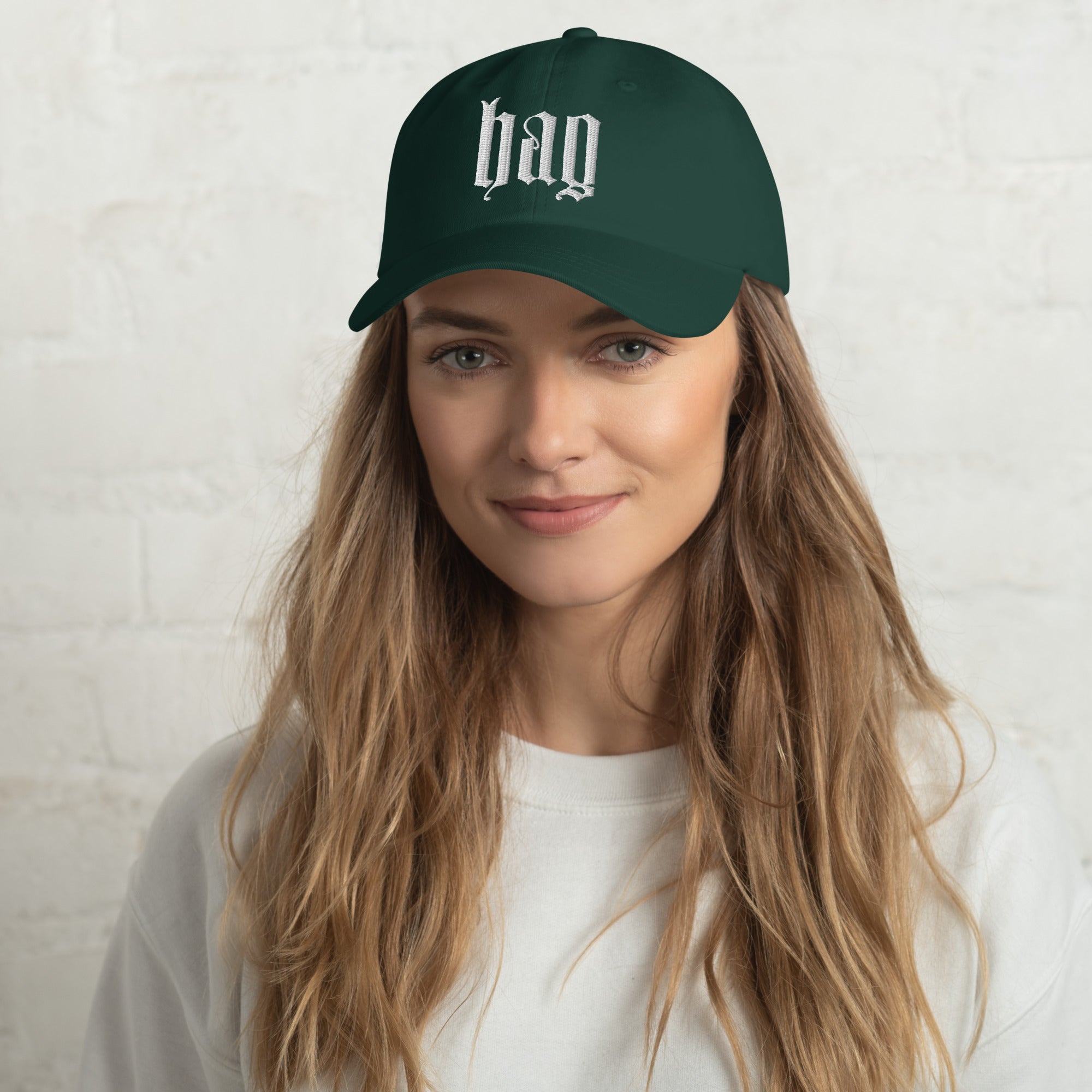 Black dad hat embroidered with the word ‘HAG’ in ornate vintage gothic lettering. Alternative fashion accessory with queer streetwear aesthetic, witchy fashion, sarcastic humor, feminist style, indie fashion, spooky cute apparel, gothic embroidery, punk inspired streetwear, adjustable baseball cap, casual everyday alternative outfit, internet humor fashion, artsy accessory, and edgy statement hat for concerts, festivals, casual wear, and alternative wardrobes.