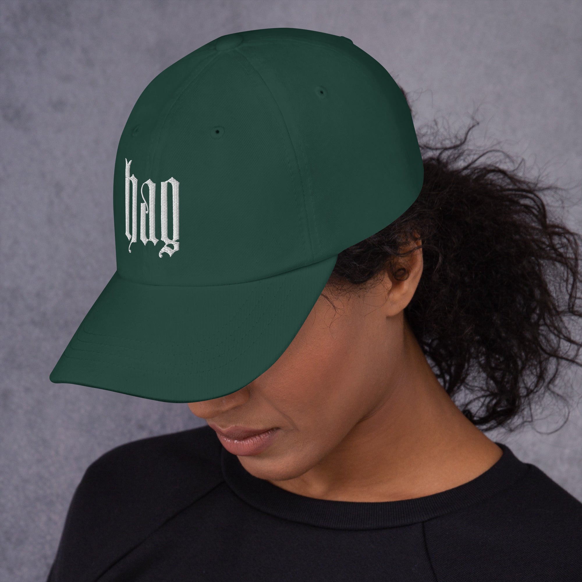 Black dad hat embroidered with the word ‘HAG’ in ornate vintage gothic lettering. Alternative fashion accessory with queer streetwear aesthetic, witchy fashion, sarcastic humor, feminist style, indie fashion, spooky cute apparel, gothic embroidery, punk inspired streetwear, adjustable baseball cap, casual everyday alternative outfit, internet humor fashion, artsy accessory, and edgy statement hat for concerts, festivals, casual wear, and alternative wardrobes.